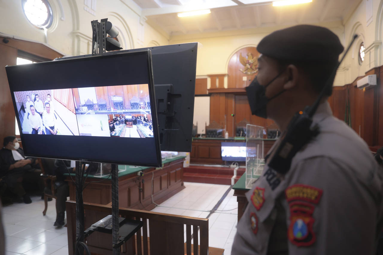 A police officer stands guard inside a court room before a trial in Surabaya, East Java, Indonesia,...