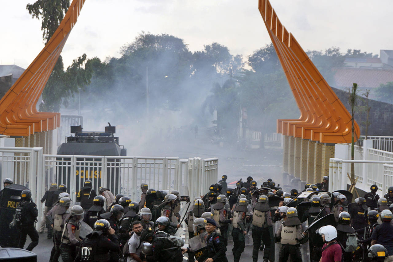 Riot police officers fire tear gas to disperse soccer supporters outside Jatidiri Stadium in Semara...
